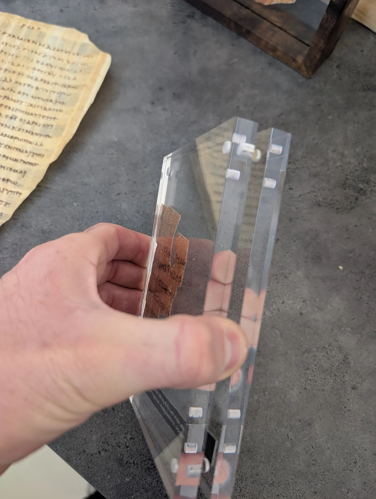 A hand holding a framed P52 manuscript replica